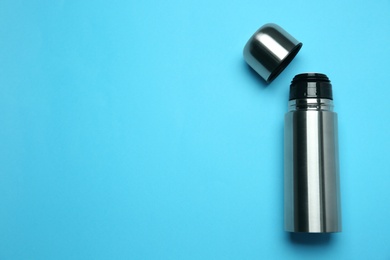Stainless steel thermos on light blue background, top view. Space for text Photo of Stainless steel thermos on light blue background, top view. Space for text
