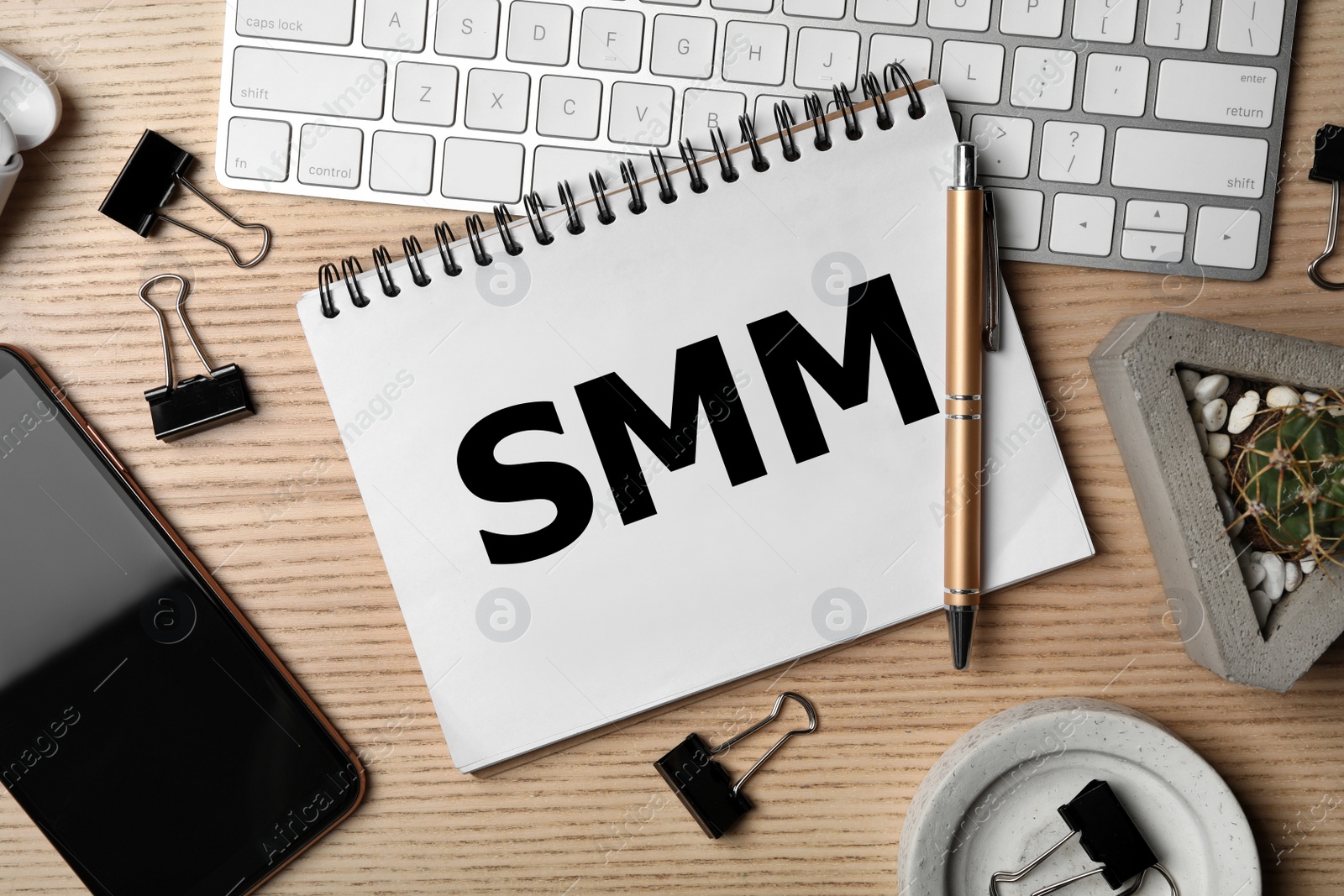 Notebook with abbreviation SMM, keyboard and smartphone on wooden table, flat lay. Social media marketing Image of Notebook with abbreviation SMM, keyboard and smartphone on wooden table, flat lay. Social media marketing