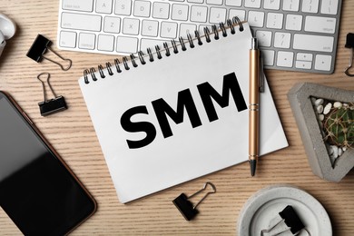 Notebook with abbreviation SMM, keyboard and smartphone on wooden table, flat lay. Social media marketing Image of Notebook with abbreviation SMM, keyboard and smartphone on wooden table, flat lay. Social media marketing