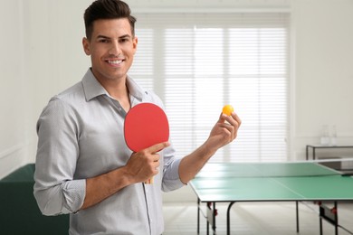 Businessman with tennis racket and ball near ping pong table in office. Space for text Photo of Businessman with tennis racket and ball near ping pong table in office. Space for text
