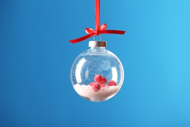 Decorative snow globe hanging on light blue background Photo of Decorative snow globe hanging on light blue background
