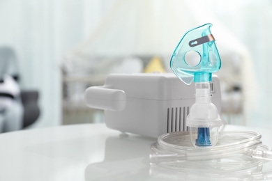 Modern nebulizer with face mask on white table in children's room. Equipment for inhalation Photo of Modern nebulizer with face mask on white table in children's room. Equipment for inhalation