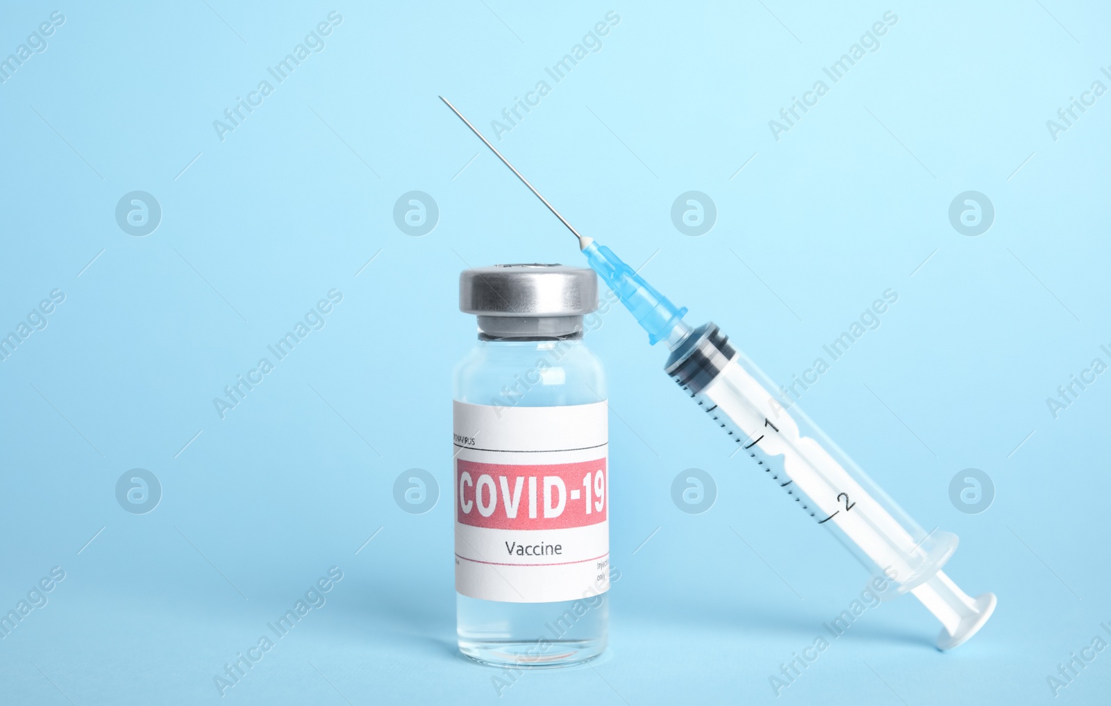 Vial with coronavirus vaccine and syringe on light blue background Photo of Vial with coronavirus vaccine and syringe on light blue background