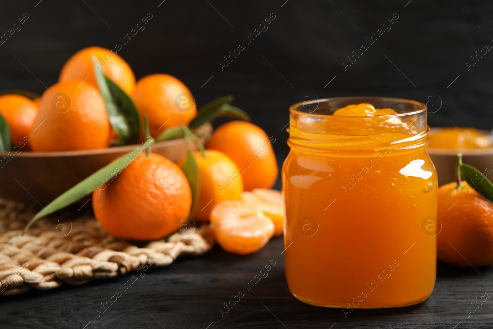 Tasty tangerine jam in glass jar on dark wooden table. Space for text Photo of Tasty tangerine jam in glass jar on dark wooden table. Space for text