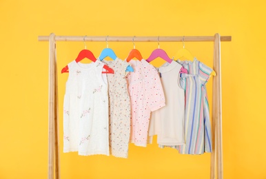 Rack with stylish children clothes on yellow background Photo of Rack with stylish children clothes on yellow background