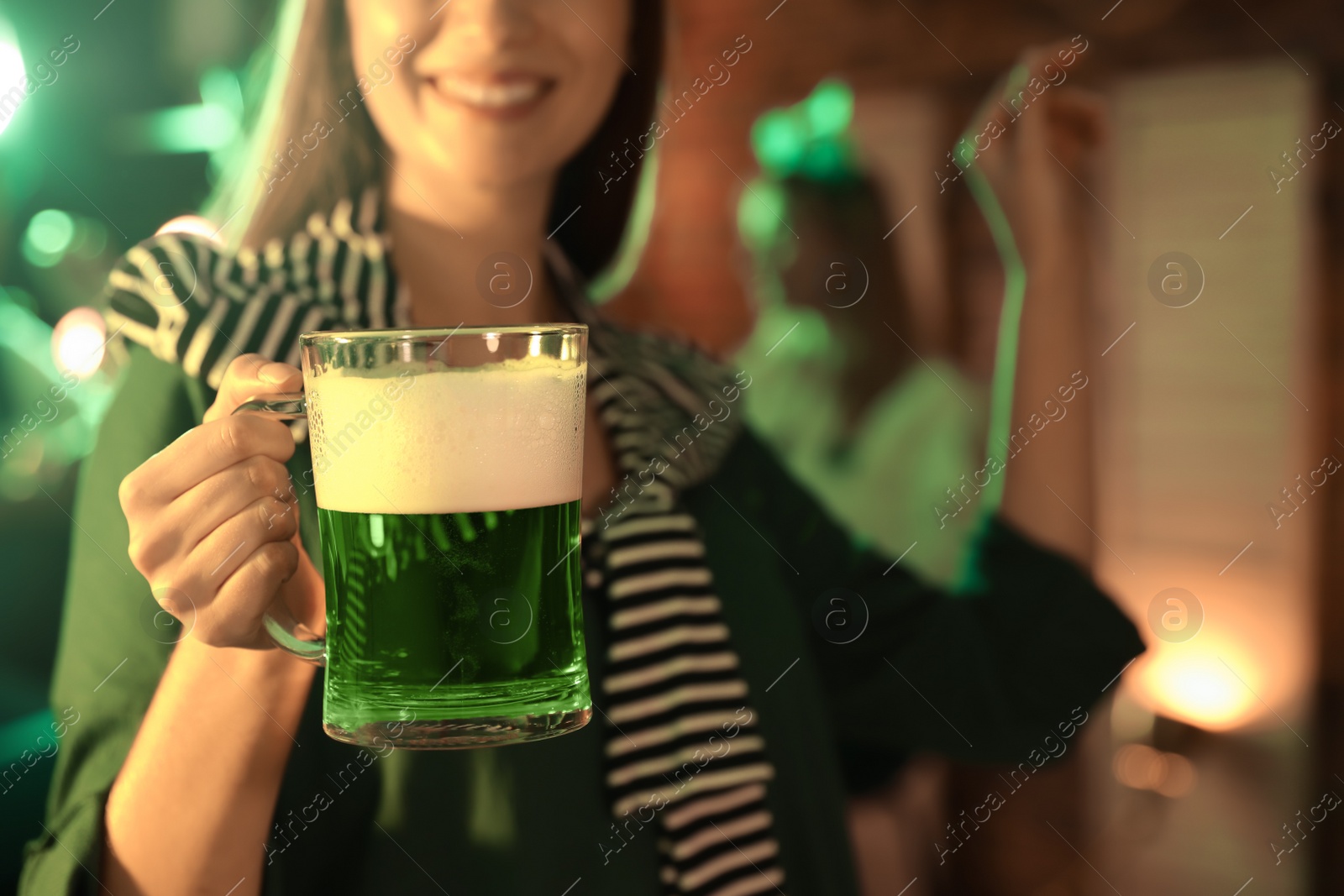 Woman with beer celebrating St Patrick's day in pub, focus on hand Photo of Woman with beer celebrating St Patrick's day in pub, focus on hand