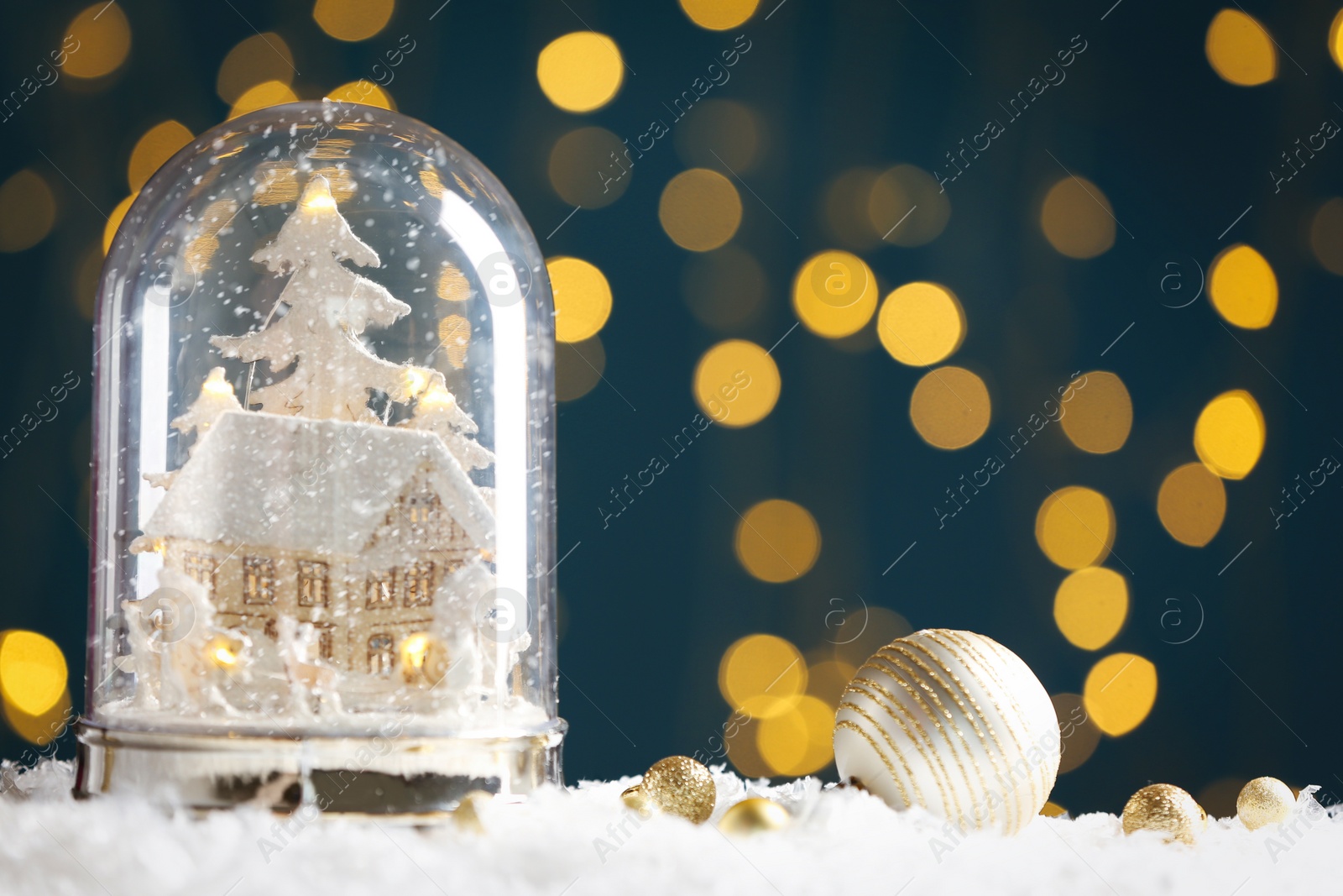 Beautiful snow globe and baubles against blurred Christmas lights. Space for text Photo of Beautiful snow globe and baubles against blurred Christmas lights. Space for text
