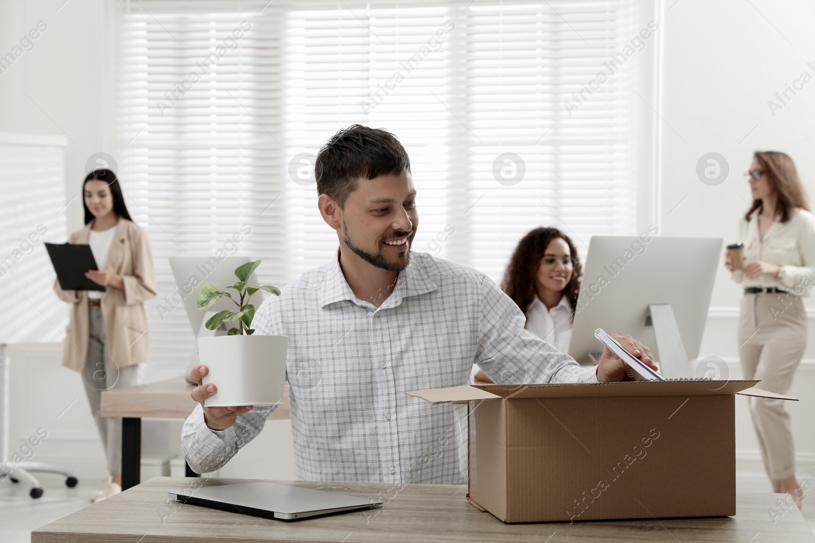 New coworker unpacking box with personal items at workplace in office Photo of New coworker unpacking box with personal items at workplace in office
