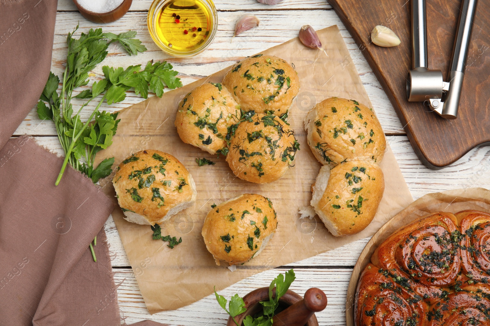 Photo of Traditional Ukrainian bread (Pampushky) with garlic on white wooden table, flat lay