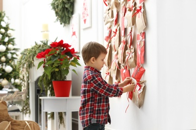 Cute little boy taking gift from Advent calendar at home. Christmas tradition Photo of Cute little boy taking gift from Advent calendar at home. Christmas tradition