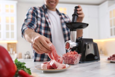 Man using modern meat grinder in kitchen, closeup Photo of Man using modern meat grinder in kitchen, closeup