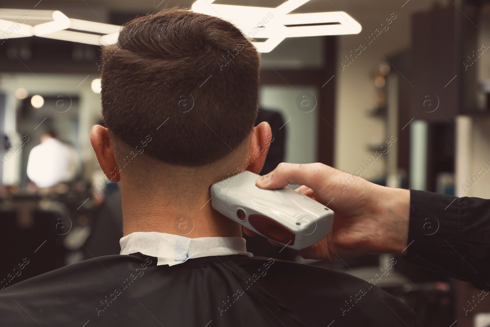 Professional hairdresser making stylish haircut in salon, back view Photo of Professional hairdresser making stylish haircut in salon, back view