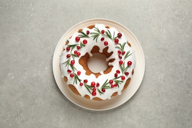 Traditional Christmas cake decorated with glaze, pomegranate seeds, cranberries and rosemary on light grey table, top view Photo of Traditional Christmas cake decorated with glaze, pomegranate seeds, cranberries and rosemary on light grey table, top view
