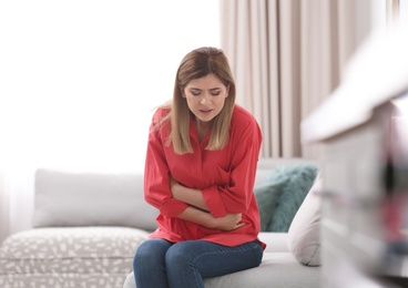 Photo of Young woman suffering from stomach ache at home