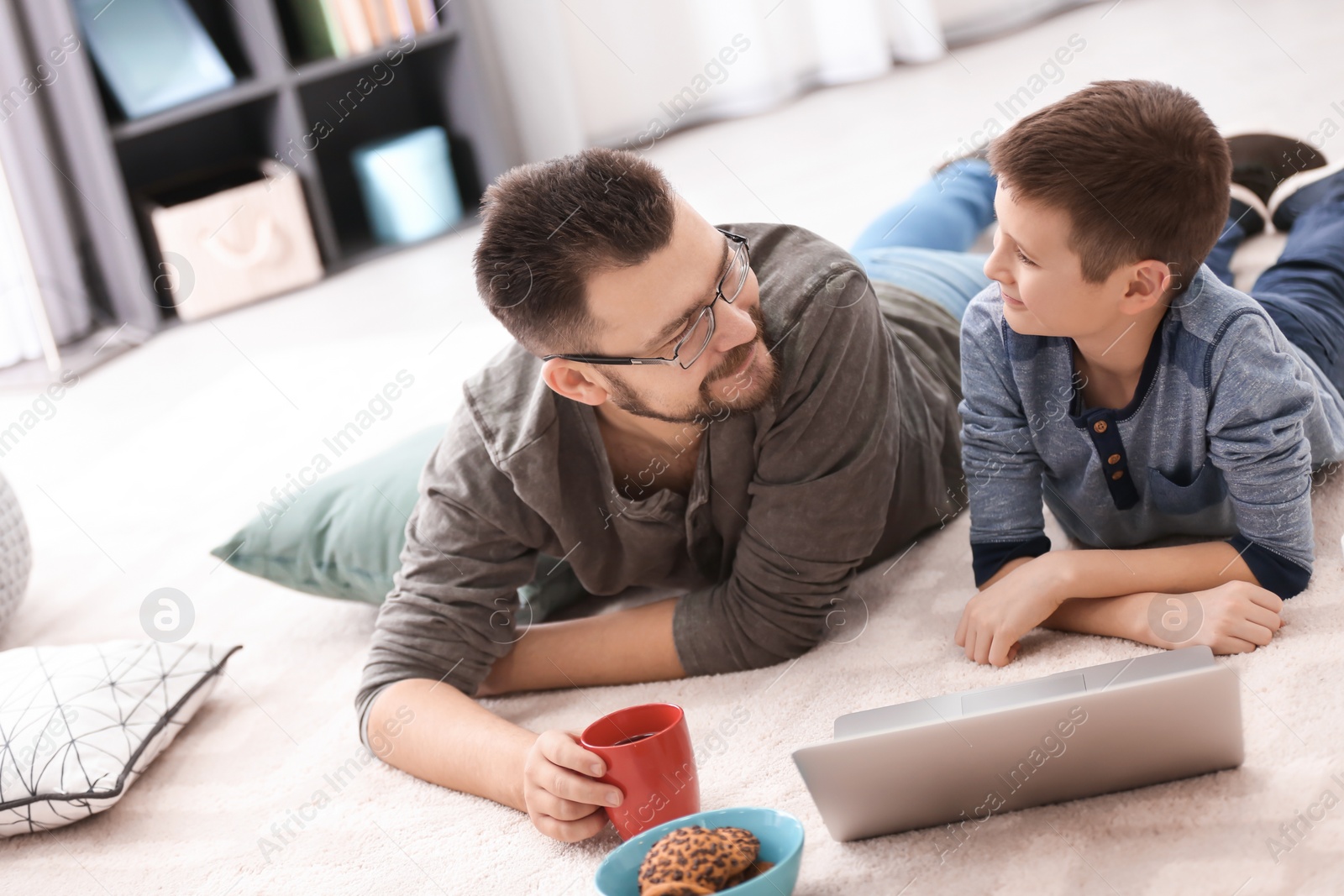 Little boy and his dad using laptop at home Photo of Little boy and his dad using laptop at home