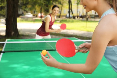 Young women playing ping pong in park, closeup Photo of Young women playing ping pong in park, closeup