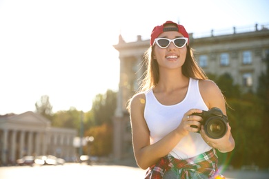 Photo of Young photographer with professional camera outdoors. Space for text