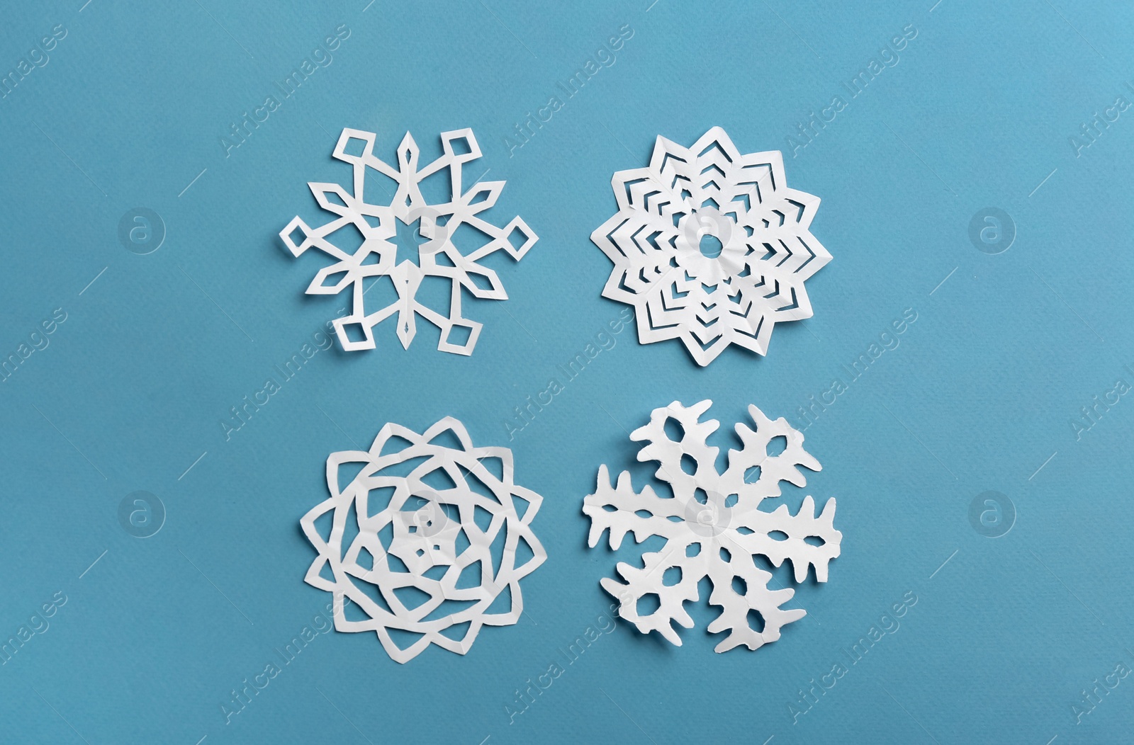 Many paper snowflakes on turquoise background, flat lay Photo of Many paper snowflakes on turquoise background, flat lay