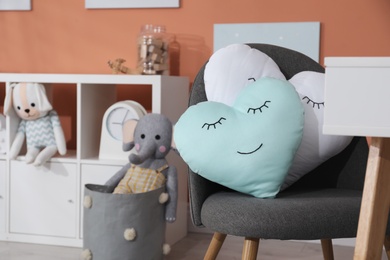 Chair with cute cushions in playroom, space for text. Interior design Photo of Chair with cute cushions in playroom, space for text. Interior design