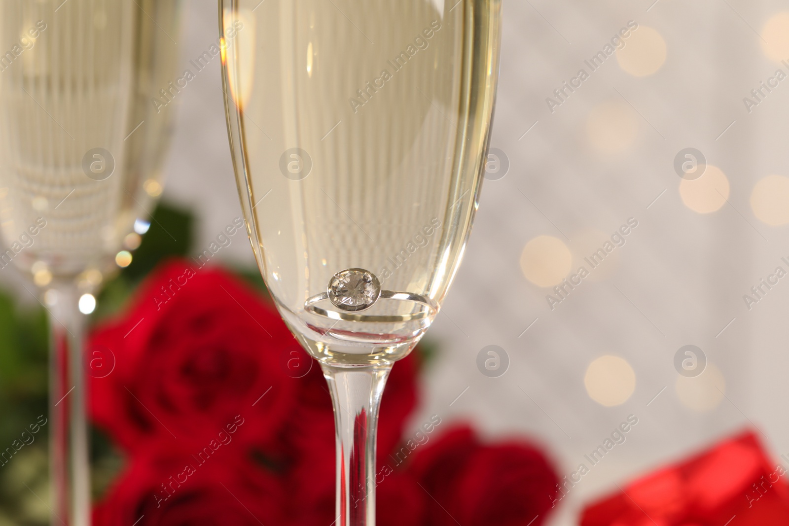 Beautiful engagement ring with gemstone in glass of sparkling wine, closeup Photo of Beautiful engagement ring with gemstone in glass of sparkling wine, closeup