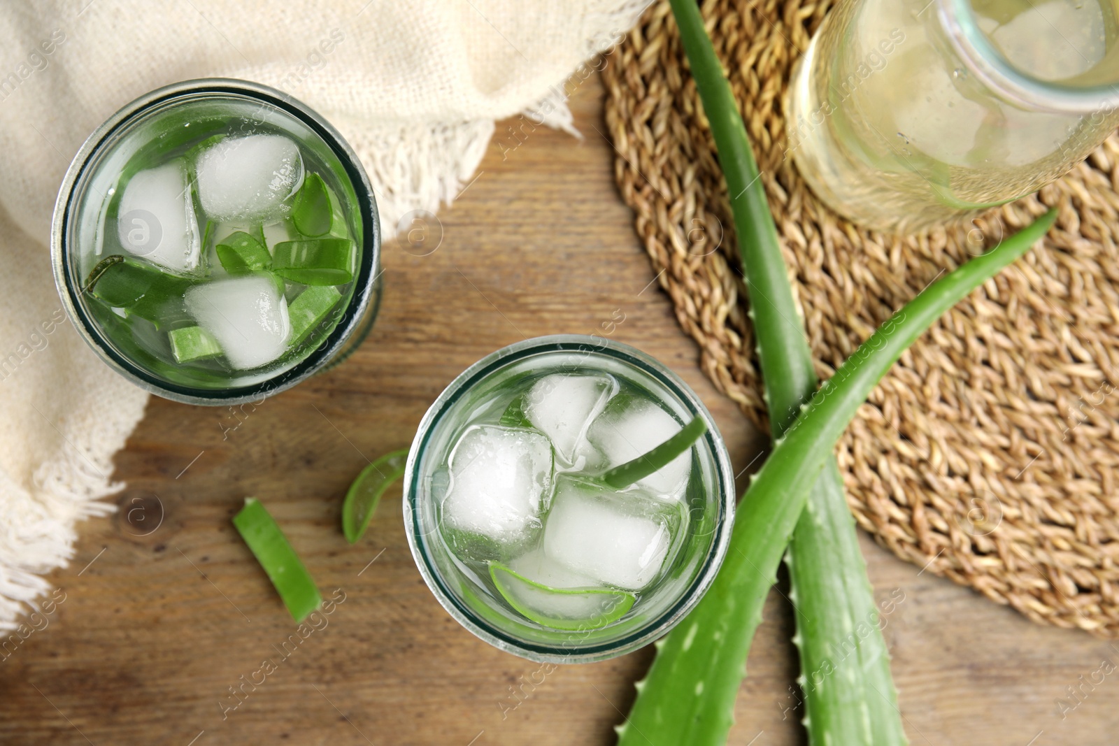 Fresh aloe drink with ice cubes on wooden table, flat lay Photo of Fresh aloe drink with ice cubes on wooden table, flat lay