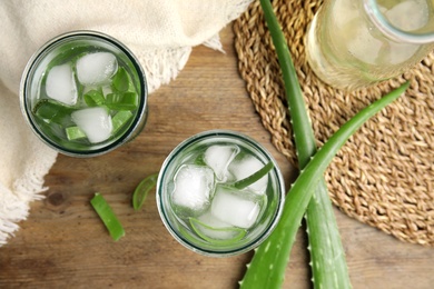 Fresh aloe drink with ice cubes on wooden table, flat lay Photo of Fresh aloe drink with ice cubes on wooden table, flat lay