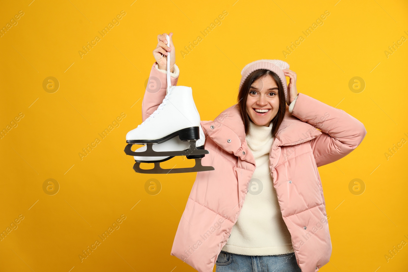 Emotional woman with ice skates on yellow background Photo of Emotional woman with ice skates on yellow background