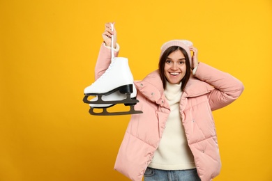 Emotional woman with ice skates on yellow background Photo of Emotional woman with ice skates on yellow background