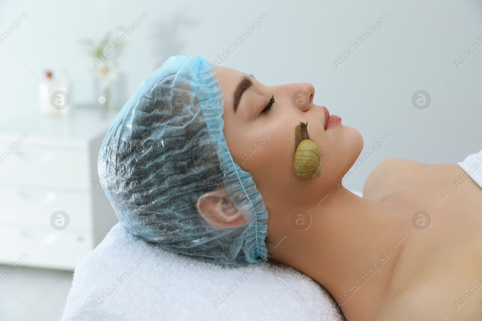 Young woman receiving snail facial massage in spa salon Photo of Young woman receiving snail facial massage in spa salon