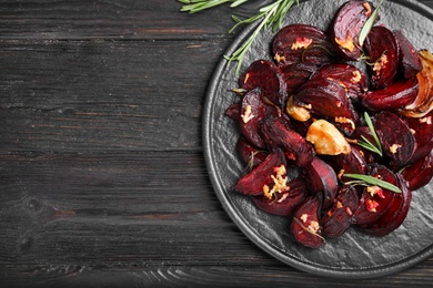Roasted beetroot slices, garlic and rosemary on black wooden table, top view. Space for text Photo of Roasted beetroot slices, garlic and rosemary on black wooden table, top view. Space for text