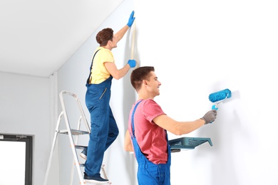 Male decorators refurbishing empty room Photo of Male decorators refurbishing empty room