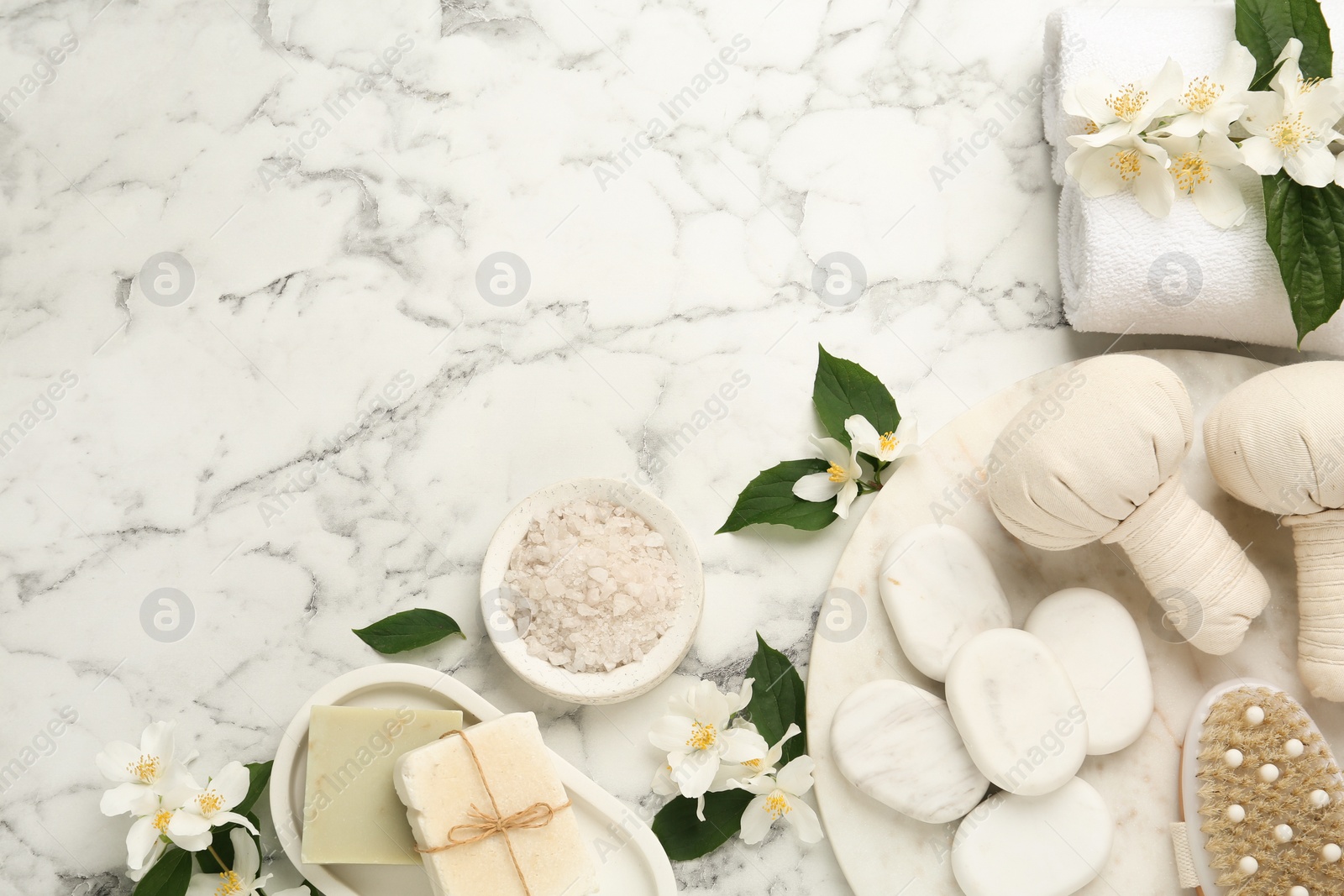 Flat lay composition with beautiful jasmine flowers and spa stones on white marble table, space for text Photo of Flat lay composition with beautiful jasmine flowers and spa stones on white marble table, space for text