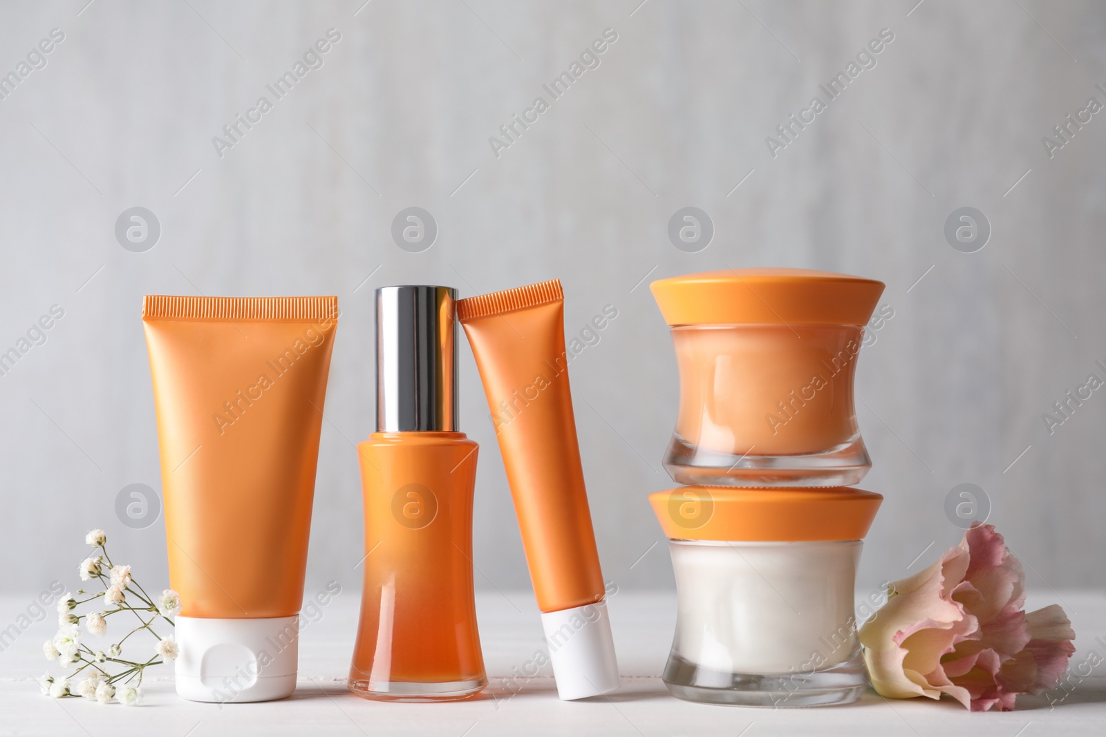 Photo of Set of luxury cosmetic products and beautiful flower on white table