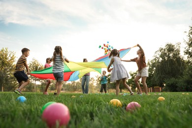 Group of children and teachers playing with rainbow playground parachute on green grass, low angle view. Summer camp activity Photo of Group of children and teachers playing with rainbow playground parachute on green grass, low angle view. Summer camp activity