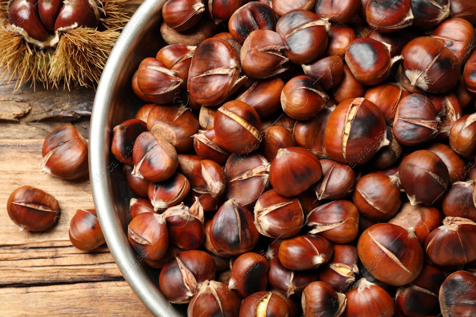 Delicious roasted edible chestnuts in bowl on wooden table, above view Photo of Delicious roasted edible chestnuts in bowl on wooden table, above view