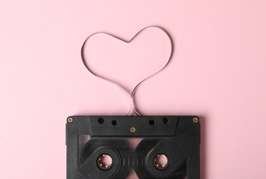 Music cassette and heart made with tape on pink background, top view. Listening love song Photo of Music cassette and heart made with tape on pink background, top view. Listening love song