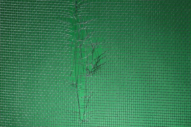 Torn window screen against green background, closeup Photo of Torn window screen against green background, closeup