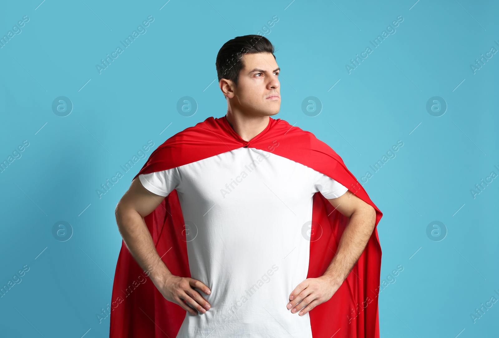 Photo of Man wearing superhero cape on light blue background