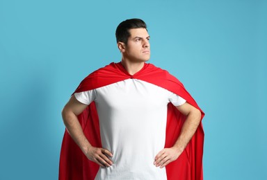 Man wearing superhero cape on light blue background Photo of Man wearing superhero cape on light blue background