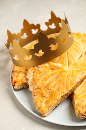 Traditional galette des Rois with paper crown on light grey marble table Photo of Traditional galette des Rois with paper crown on light grey marble table