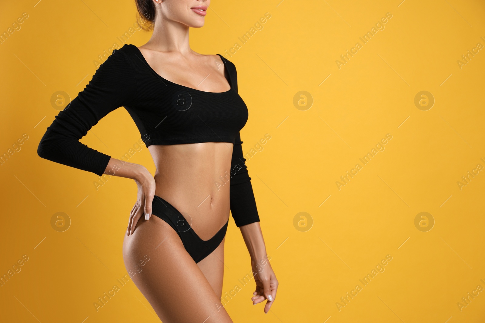 Woman in black sexy panties on yellow background, closeup. Space for text Photo of Woman in black sexy panties on yellow background, closeup. Space for text