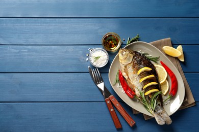 Tasty homemade roasted crucian carp served on blue wooden table, flat lay with space for text. River fish Photo of Tasty homemade roasted crucian carp served on blue wooden table, flat lay with space for text. River fish