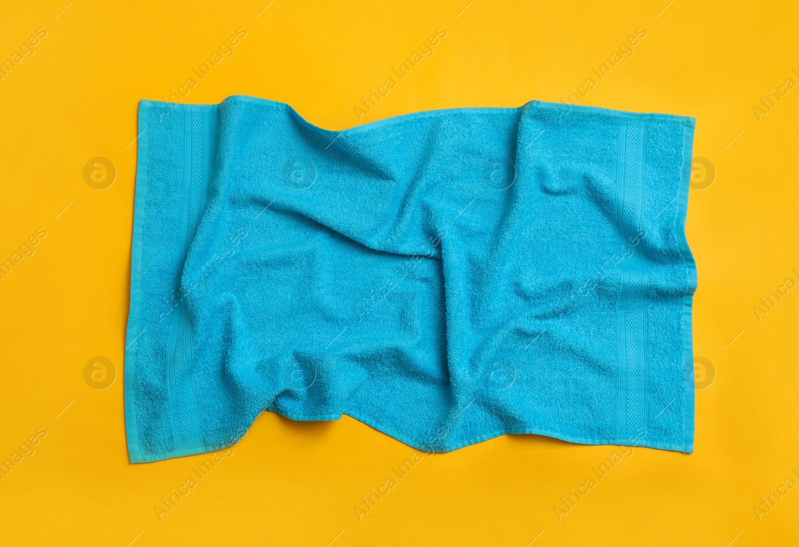 Crumpled light blue beach towel on yellow background, top view Photo of Crumpled light blue beach towel on yellow background, top view