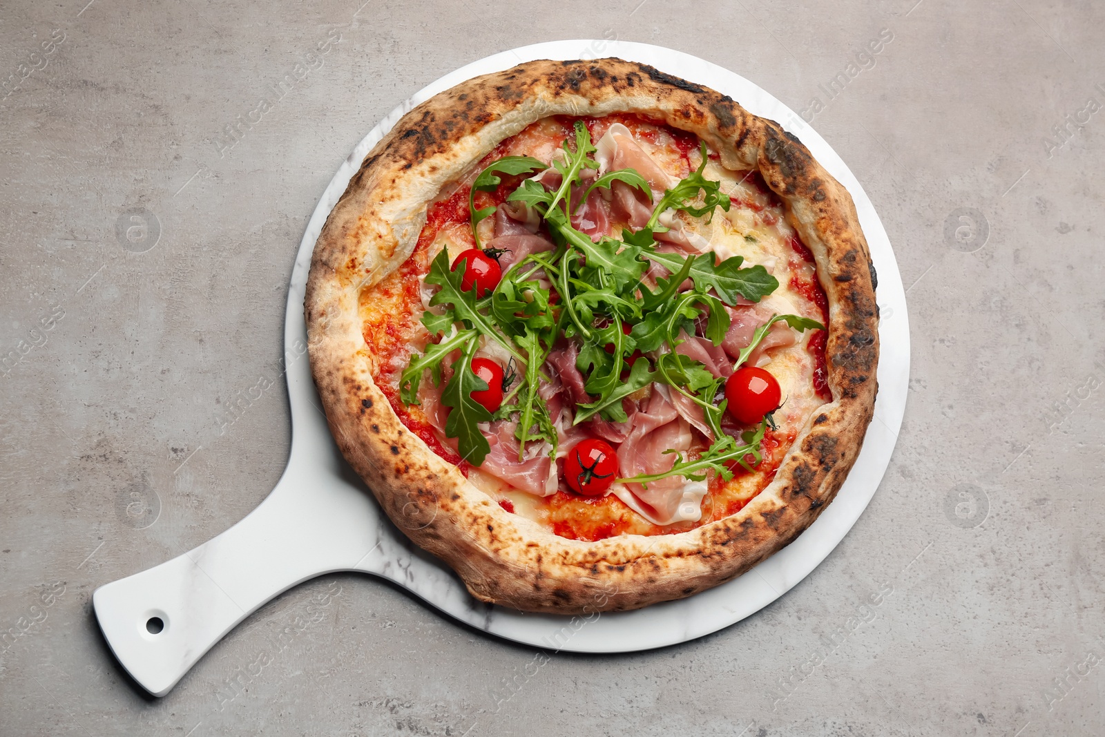 Tasty pizza with meat and arugula on grey table, top view Photo of Tasty pizza with meat and arugula on grey table, top view
