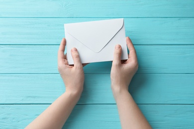 Woman with white paper envelope at light blue wooden table, top view Photo of Woman with white paper envelope at light blue wooden table, top view