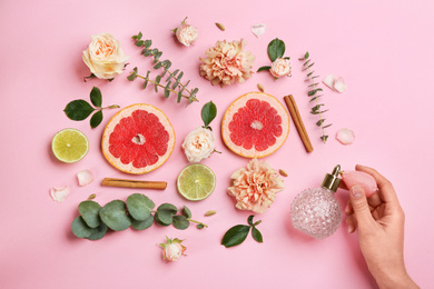 Top view of woman spraying perfume on pink background, flowers and citrus fruits representing aroma Photo of Top view of woman spraying perfume on pink background, flowers and citrus fruits representing aroma