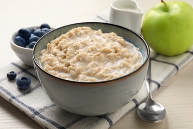 Tasty oatmeal porridge served on light wooden table Photo of Tasty oatmeal porridge served on light wooden table