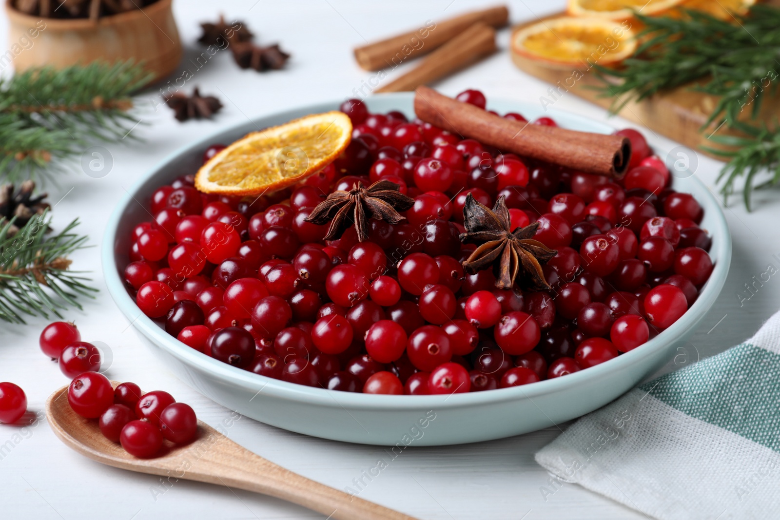 Fresh ripe cranberries and spices on white wooden table Photo of Fresh ripe cranberries and spices on white wooden table