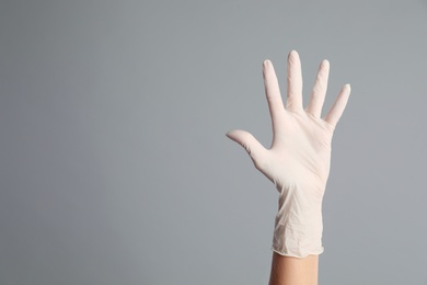 Doctor wearing medical gloves on grey background, closeup. Space for text Photo of Doctor wearing medical gloves on grey background, closeup. Space for text