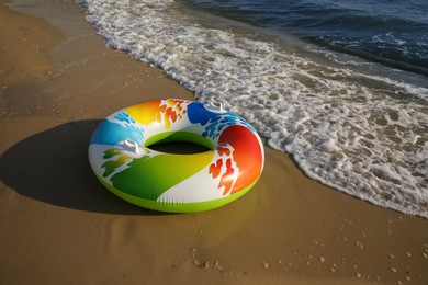 Bright inflatable ring on sandy beach near sea, space for text Photo of Bright inflatable ring on sandy beach near sea, space for text